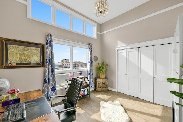 office featuring a notable chandelier, a city view, baseboards, and light wood-style floors