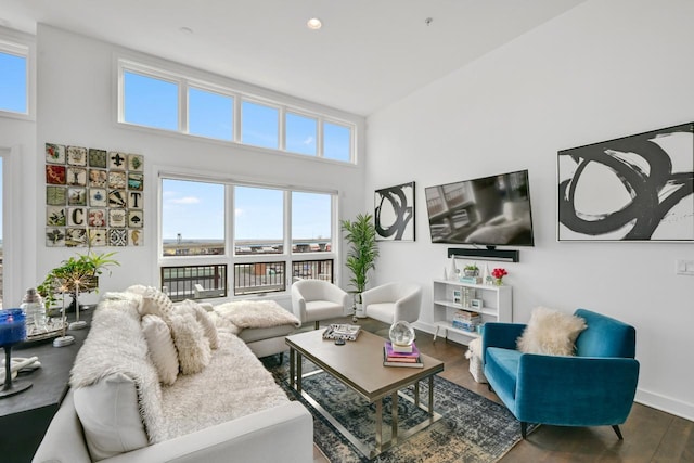 living room featuring recessed lighting, wood finished floors, a towering ceiling, and baseboards