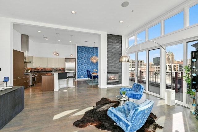 living room featuring a city view, dark wood finished floors, a towering ceiling, a multi sided fireplace, and baseboards