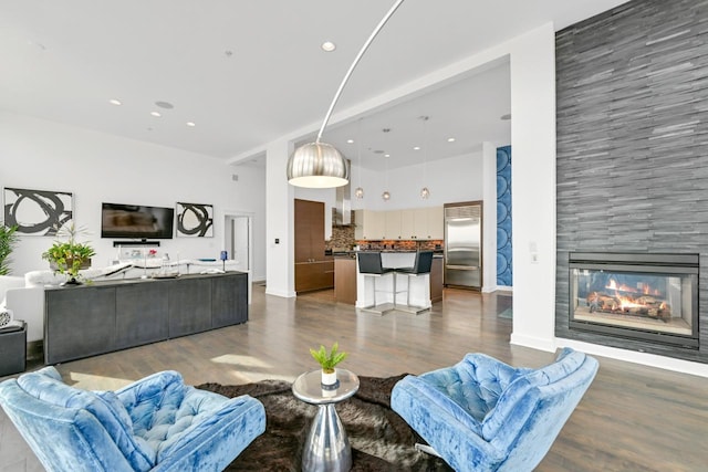 living area with dark wood-style floors, recessed lighting, a towering ceiling, a multi sided fireplace, and baseboards