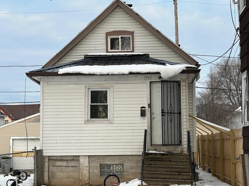 exterior space featuring entry steps, fence, and metal roof