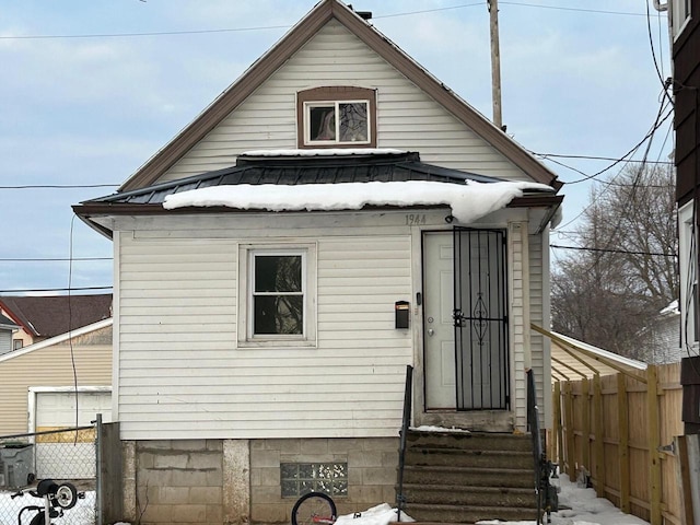 exterior space featuring entry steps, fence, and metal roof