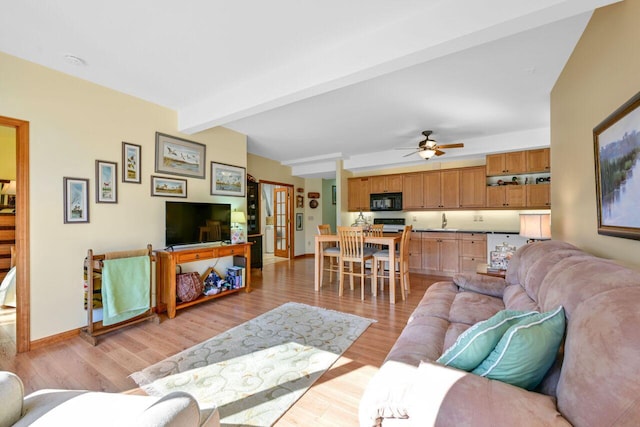 living room featuring a ceiling fan, light wood-style flooring, baseboards, and beam ceiling