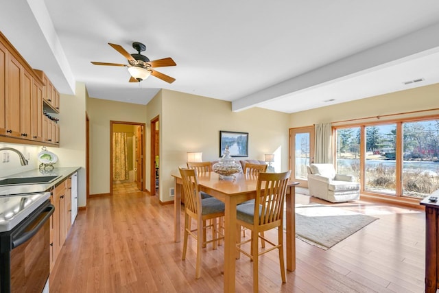 dining room featuring light wood-type flooring, baseboards, visible vents, and beam ceiling