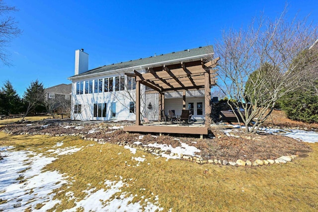 snow covered rear of property featuring a chimney and a pergola