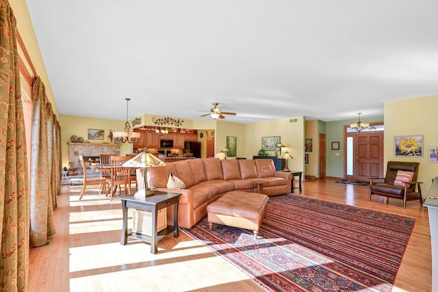 living area featuring ceiling fan with notable chandelier, light wood finished floors, and visible vents