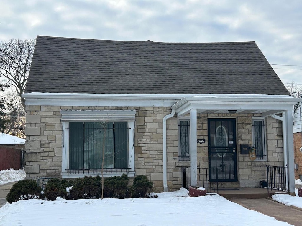 view of front of home featuring a shingled roof and stone siding