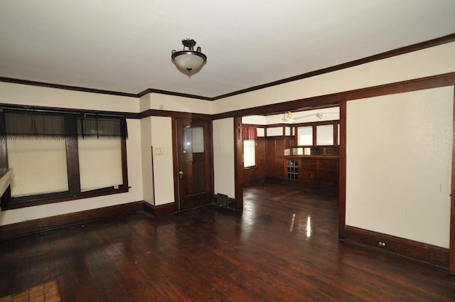 empty room with baseboards, dark wood finished floors, and crown molding