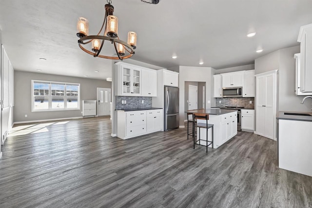 kitchen with dark countertops, white cabinetry, a kitchen island, and appliances with stainless steel finishes