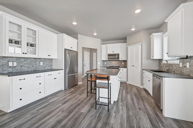 kitchen featuring stainless steel appliances, dark countertops, white cabinets, and a kitchen island