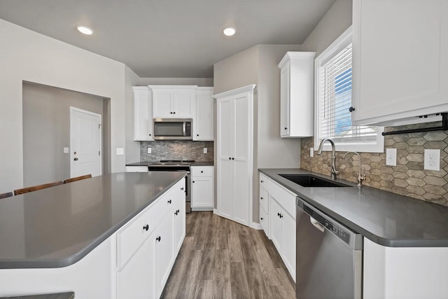 kitchen with dark countertops, white cabinetry, appliances with stainless steel finishes, and a sink