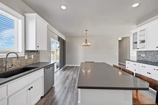 kitchen featuring dark countertops, a sink, a kitchen island, and dishwasher