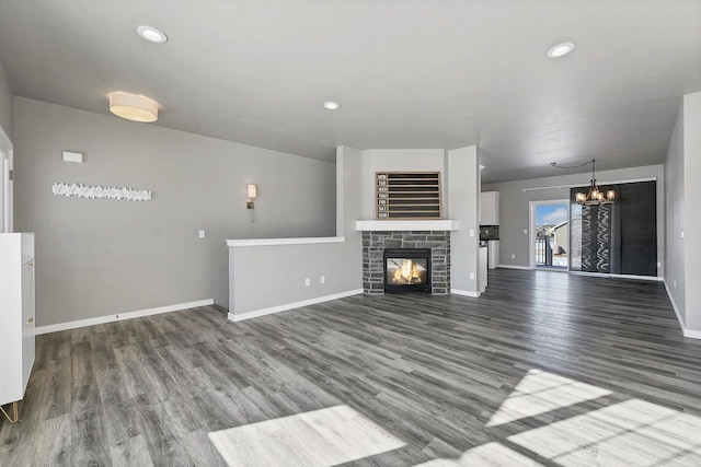 unfurnished living room with a chandelier, wood finished floors, and baseboards