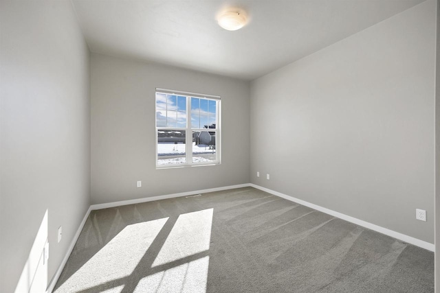 carpeted spare room featuring baseboards