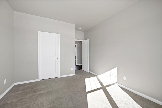 unfurnished bedroom with dark carpet and baseboards