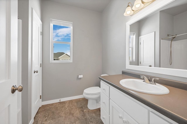 bathroom with toilet, vanity, and baseboards