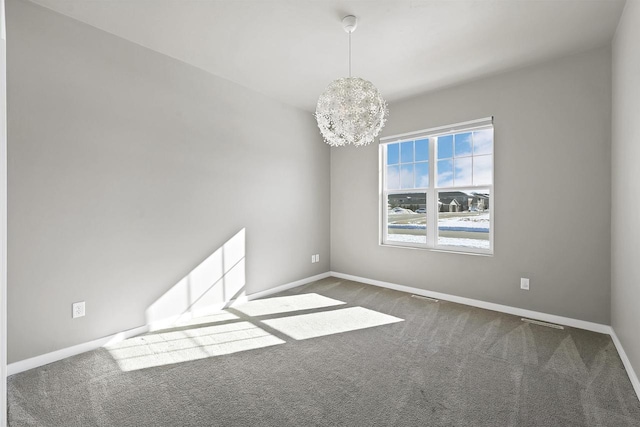 empty room with baseboards, dark colored carpet, and a notable chandelier