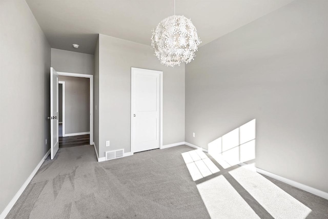 unfurnished bedroom featuring baseboards, carpet floors, visible vents, and an inviting chandelier