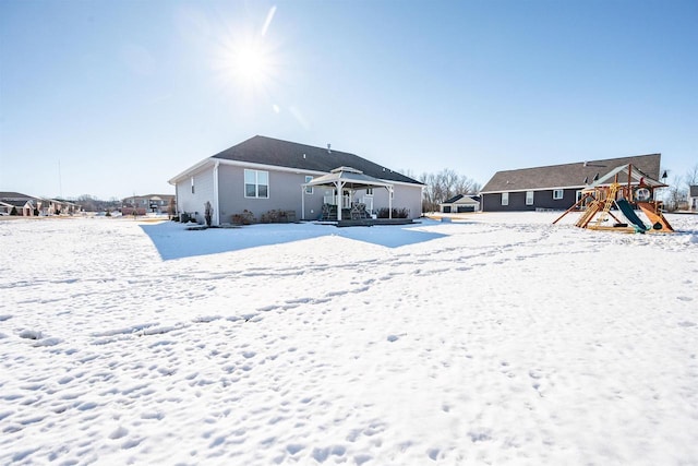 snow covered rear of property featuring a playground