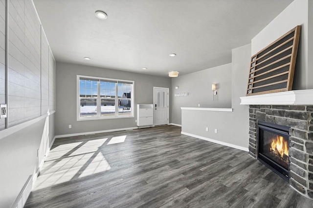 unfurnished living room with recessed lighting, a fireplace, dark wood finished floors, and baseboards