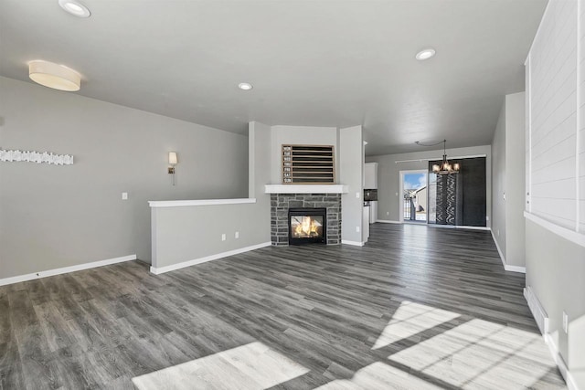 unfurnished living room with baseboards, a fireplace, dark wood finished floors, and an inviting chandelier