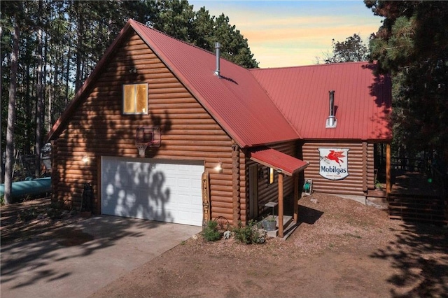 log cabin featuring metal roof, log exterior, driveway, and a garage