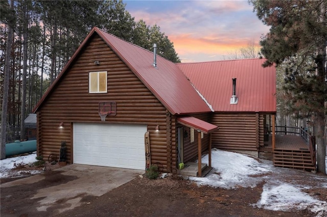 view of front of home featuring metal roof, concrete driveway, log siding, and a garage