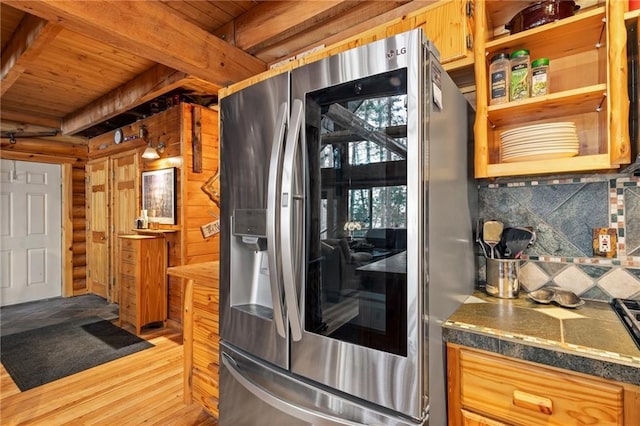 kitchen with wood ceiling, log walls, tasteful backsplash, beamed ceiling, and stainless steel fridge