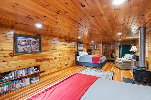 bedroom featuring light wood finished floors, recessed lighting, a wood stove, wood walls, and wooden ceiling