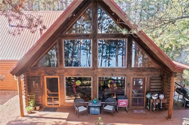 rear view of property featuring metal roof, log exterior, and a wooden deck