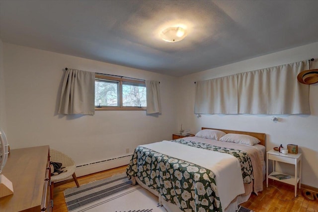 bedroom with wood finished floors and a baseboard radiator