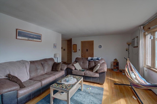 living area with an AC wall unit and light wood-style flooring