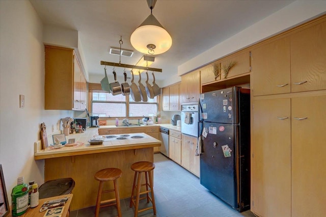 kitchen with visible vents, a peninsula, freestanding refrigerator, oven, and stainless steel dishwasher