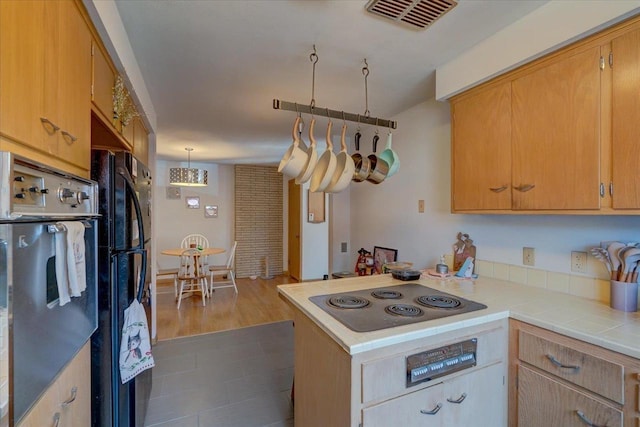 kitchen with tile countertops, visible vents, dark wood finished floors, a peninsula, and stainless steel appliances