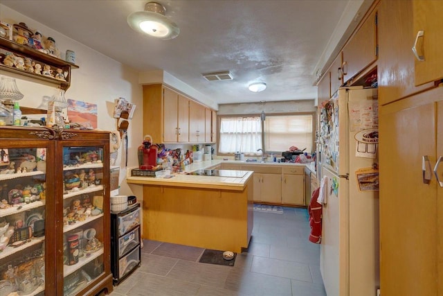 kitchen featuring visible vents, freestanding refrigerator, a peninsula, light countertops, and black electric stovetop