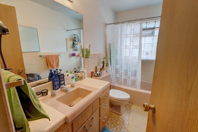 full bath featuring tile walls, a wainscoted wall, toilet, shower / bath combo with shower curtain, and vanity