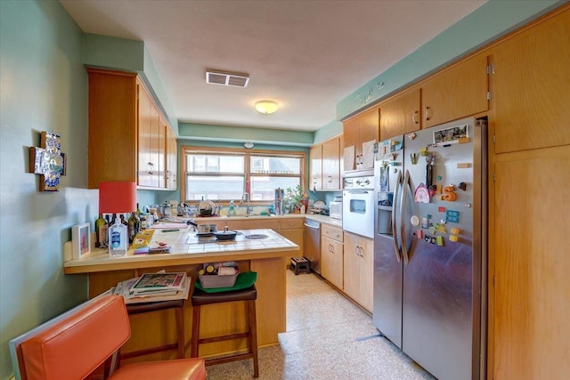 kitchen featuring light floors, visible vents, a peninsula, tile counters, and appliances with stainless steel finishes