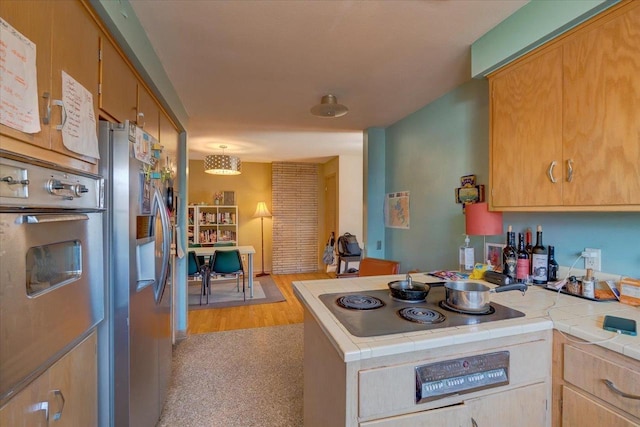 kitchen featuring tile counters, a peninsula, and appliances with stainless steel finishes