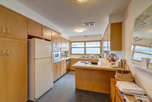 kitchen featuring visible vents, white appliances, and a peninsula