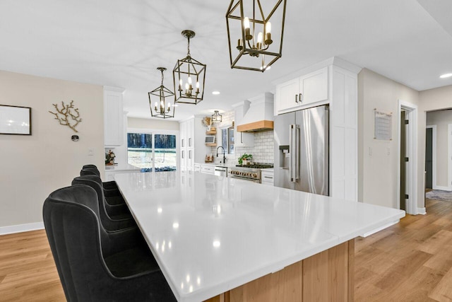 kitchen with premium range hood, a sink, light countertops, high quality appliances, and a chandelier