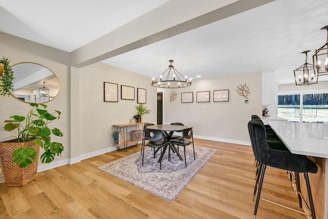 dining area with a chandelier, light wood finished floors, and baseboards