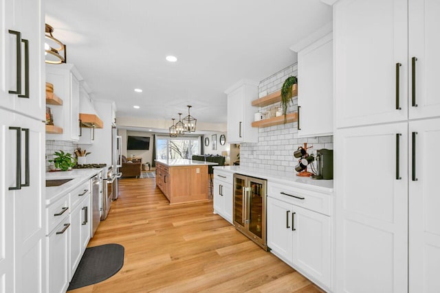 kitchen with open shelves, wine cooler, white cabinets, and light wood finished floors