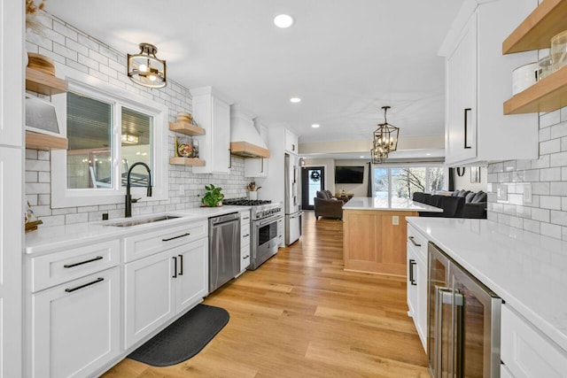 kitchen featuring a sink, open shelves, custom range hood, and stainless steel appliances