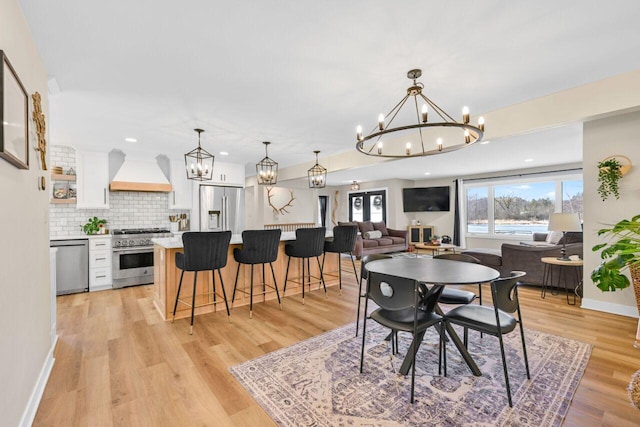 dining room featuring an inviting chandelier, recessed lighting, light wood-style floors, and baseboards