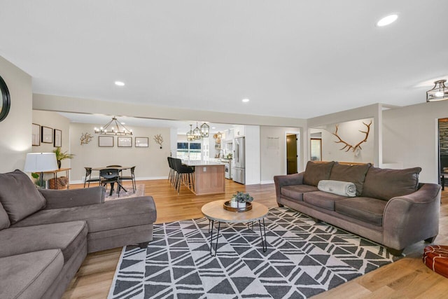 living area featuring recessed lighting, baseboards, light wood-style floors, and an inviting chandelier