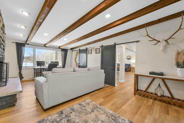 living area featuring light wood-type flooring, a barn door, lofted ceiling with beams, and recessed lighting