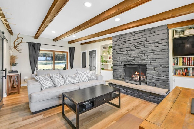 living area with built in shelves, beam ceiling, wood finished floors, recessed lighting, and a fireplace