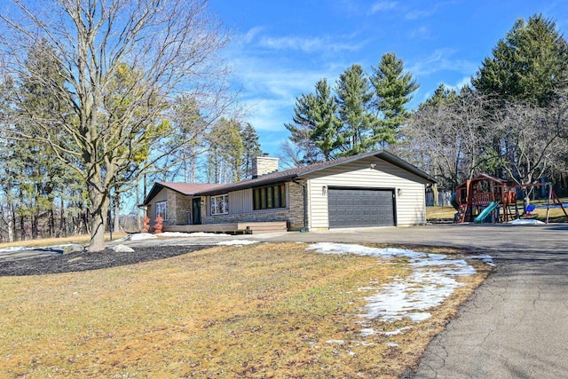 view of front facade with a front lawn, driveway, a chimney, and an attached garage