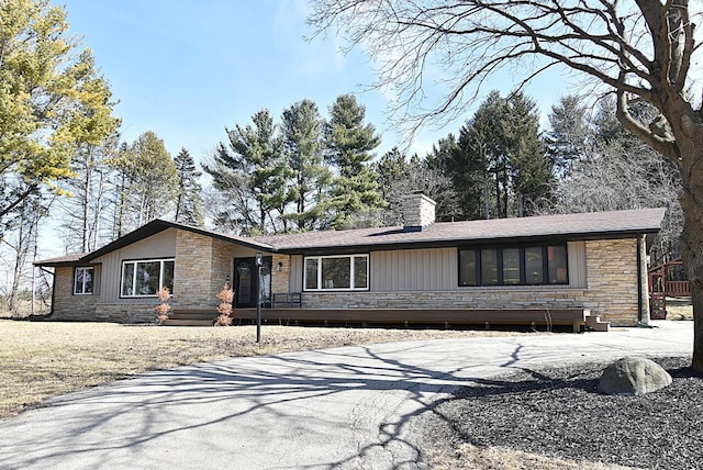 mid-century home featuring stone siding and a chimney