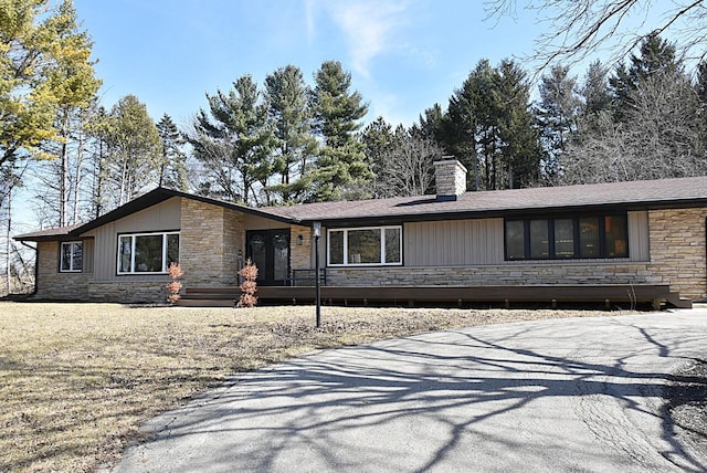 view of front of home with stone siding and a chimney